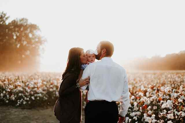 Casal beija o filho junto às flores